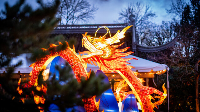 Portland, United States - 17 February 2026: View of a vibrant, illuminated dragon sculpture against a backdrop of traditional Chinese architecture at Lan Su Chinese Garden.