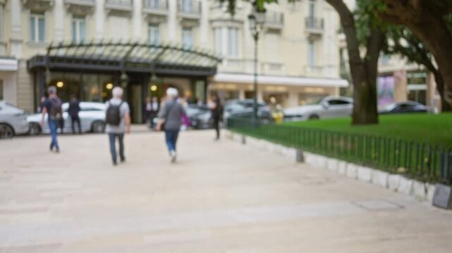 Blurry outdoor scene with people walking in monaco street, featuring luxury cars and elegant buildings, emphasizing an out-of-focus urban setting and relaxed atmosphere.