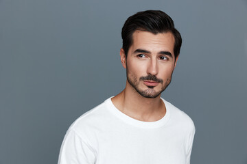 Stylish young man looking to side with a thoughtful expression, wearing a white t-shirt against a...