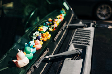 Colorful rubber ducks placed on the windshield of a parked car during a sunny day © tisaeff