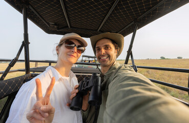 Man and a woman are sitting in a off-road car. The man is wearing a green hoodie during safari in park in South Africa © xamnex
