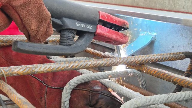 Slow motion extreme close up of welding sparks as a rebar is attached to a steel spacer on a foundation.