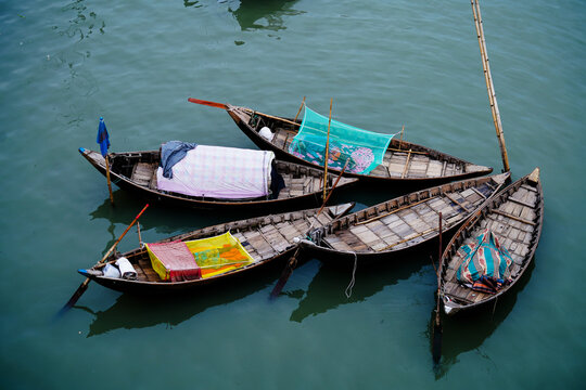 Keraniganj, Bangladesh - 23 September 2022: View of small wooden boats clustered together, their colorful coverings reflecting on the rippling water's surface.