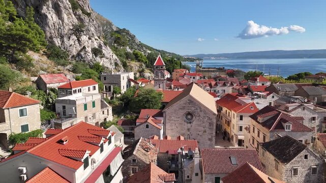 Drone close aerial of St Michael church tower in Omi&scaron; highlighting architectural details and historic structure rising above old town buildings