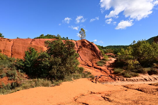 Paysage spectaculaire du Colorado proven&ccedil;al dans le Luberon, avec falaises d&rsquo;ocre aux teintes rouges et orang&eacute;es, illustrant un d&eacute;cor naturel unique et typique de la Provence.