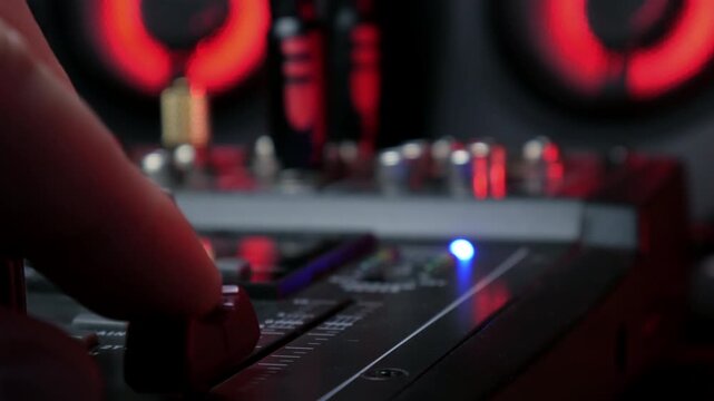 Sound engineer hands adjusting knobs and faders on audio mixer in recording studio.
