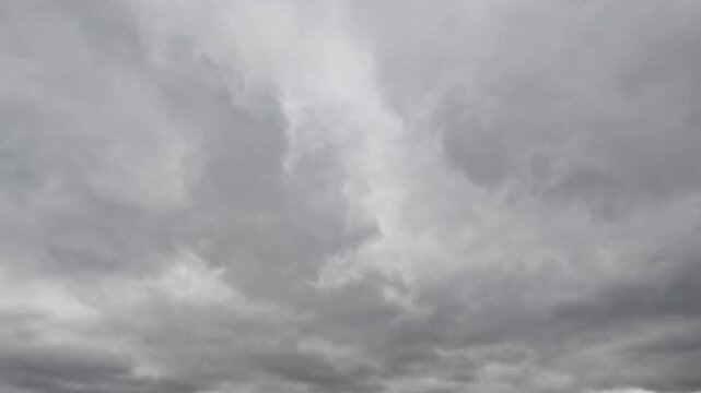 Seamless loop of dark grey overcast storm clouds moving across the sky
