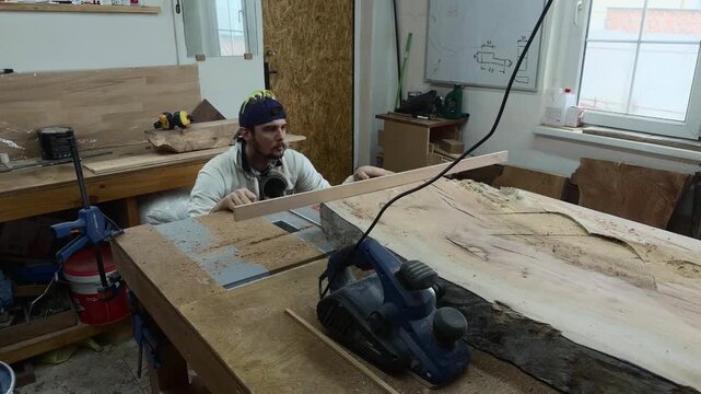 Carpenter Inspecting Timber Slab Flatness with Straight Edge in Workshop Medium Shot