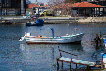 Obraz premium a traditional white and blue wooden fishing boat moored in a calm harbor, featuring a rustic wooden and metal pier in the foreground 