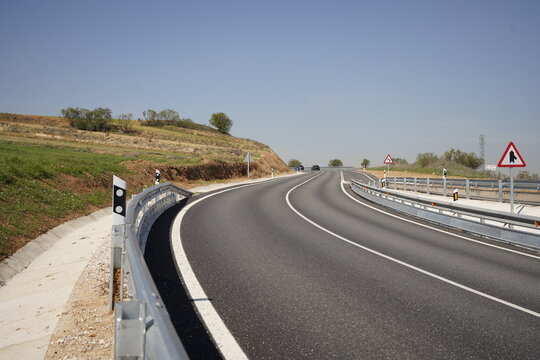 Una carretera en zona de campo con curva y varios coches circulando, referencia a transporte y calidad del asfalto