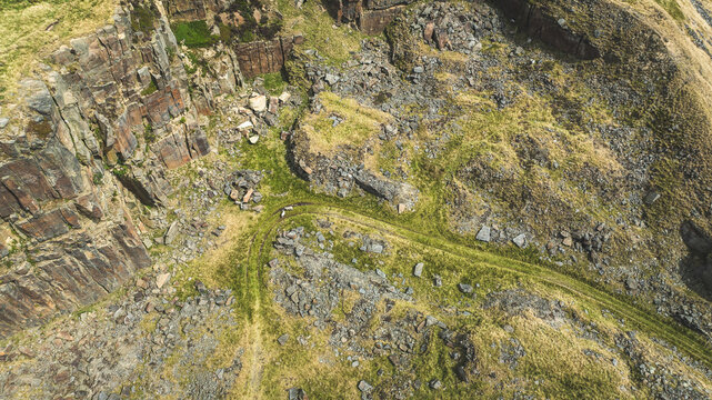 Aerial view of a rugged, rocky hillside with a winding path and sparse vegetation
