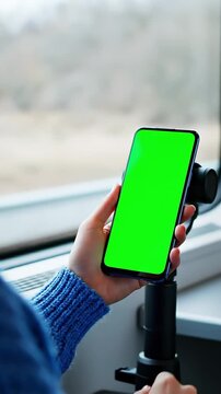 Iphone Mockup, Blue sweater holds smartphone with green screen on mount to vehicle window, neutral view during daytime travel