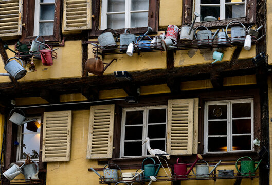 Watering cans hang below the windows of a half-timbered building in Colmar, France.