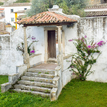 Europe, Portugal, Obidos.  Dark purple bougainvillea vine growing along side the entrance of a home in the walled town.