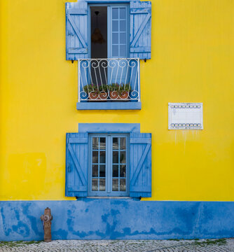 Europe, Portugal, Aveiro.  Colorful yellow building with bright blue shutters along the canal in Aveiro.