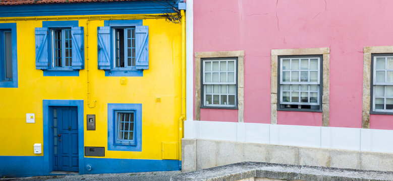Europe, Portugal, Aveiro.  Colorful yellow building with bright blue shutters and pink building along the canal in Aveiro.
