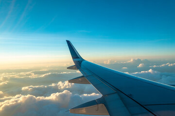 Obraz premium Airplane wing extends over a vast expanse of soft clouds bathed in golden hour light