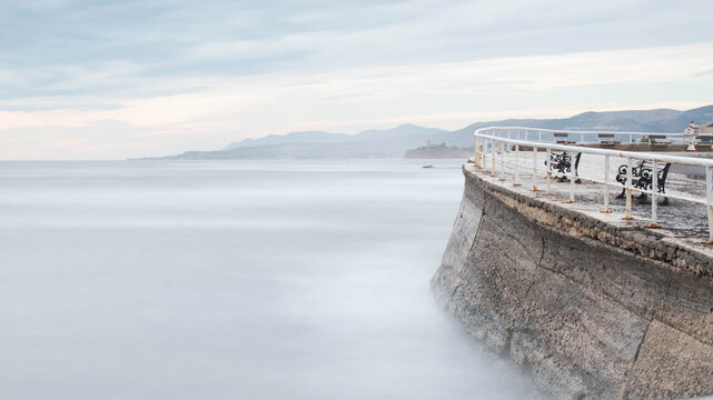 Minimalist long exposure of benches on a misty sea coast