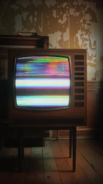 A vintage television displaying static on a wooden stand in a dimly lit room with peeling wallpaper