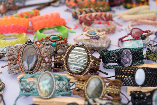 Handmade macrame bracelets with natural stones displayed at an outdoor market stall