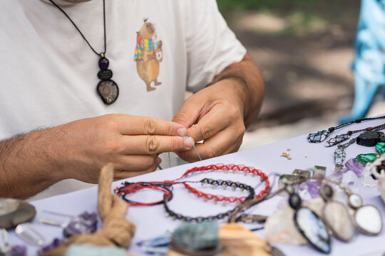 Artisan meticulously crafts handmade macrame bracelets and necklaces with colorful threads and stones