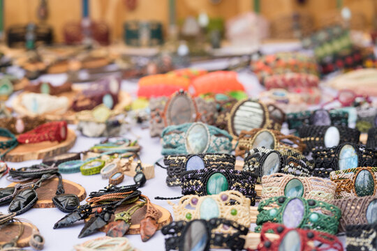 Artisan crafting intricate macrame bracelets with natural stones at an outdoor market stall