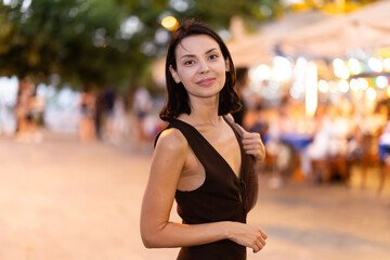 Fototapeta premium Woman walks in vicinity of Citadel park, spend time in public urban space. Atmosphere of relaxation, idleness, entertainment. Electric street lighting..