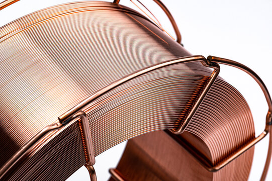 Bulk copper welding wire on metal basket frame spool. Close up of professional copper coated welding wire on a metallic wire reel.