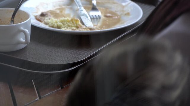 Cleaning up a restaurant table with leftover food on wooden surface