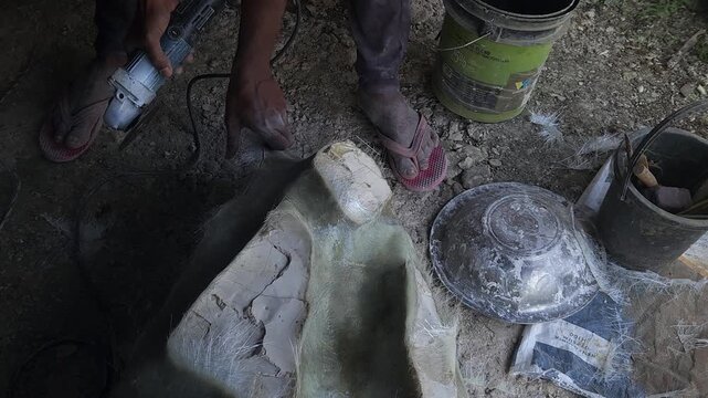 Close-up of a skilled artisan shaping a fibre sculpture using a power tool in a workshop, captured in slow motion. The scene highlights precision craftsmanship, manual labor, India