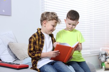 Naklejka premium Cute little boys reading book together indoors