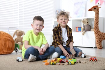 Fototapeta premium Cute little boys playing with toys on floor indoors