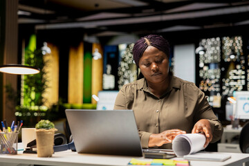 Obraz premium Black employee proofreading and fact checking financial numbers, reviewing archived files after hours in the strategy room. Evaluating data on reports, researching and organizing agenda.