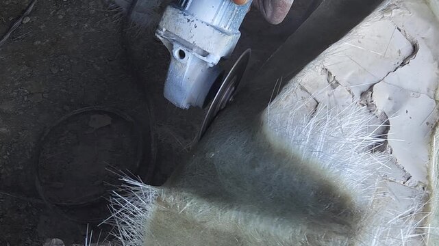 Close-up of a skilled artist using an angle grinder to cut and shape a fibre sculpture, captured in slow motion. The scene highlights precision craftsmanship, manual work, and industrial tools, India