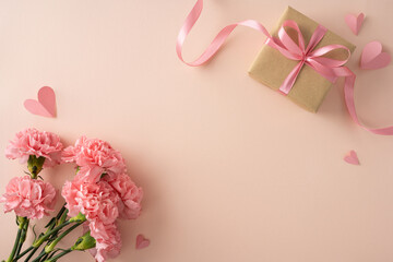 Happy Mother's Day flat lay featuring pink carnations, a wrapped gift box tied with ribbon and...