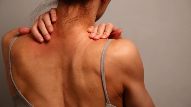 Health sport body woman doing massage with hands her neck, shoulders, upper back. Fit naked muscles model in bra isolated in studio light with copy space. Back view closeup