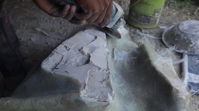 Close-up of a skilled artist using an angle grinder to cut and shape a fibre sculpture, captured in slow motion. The scene highlights precision craftsmanship, manual work, and industrial tools, India