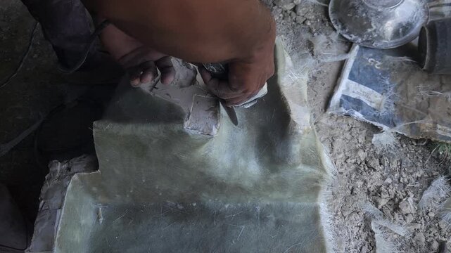 Close-up of a skilled artist using an angle grinder to cut and shape a fibre sculpture, captured in slow motion. The scene highlights precision craftsmanship, manual work, and industrial tools, India