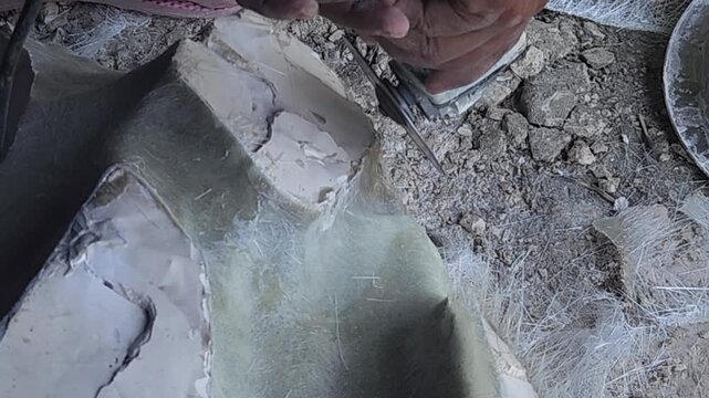 Close-up of a skilled artist using an angle grinder to cut and shape a fibre sculpture, captured in slow motion. The scene highlights precision craftsmanship, manual work, and industrial tools, India