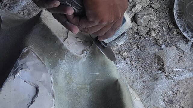 Close-up of a skilled artist using an angle grinder to cut and shape a fibre sculpture, captured in slow motion. The scene highlights precision craftsmanship, manual work, and industrial tools, India