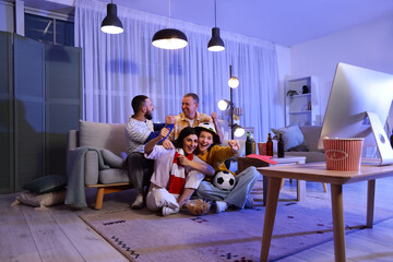 Happy soccer fans with ball watching game at home in evening © Pixel-Shot