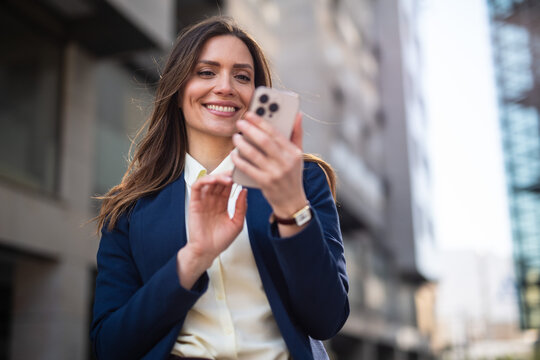 Happy businesswoman using smartphone on city street