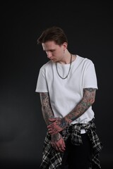 Fototapeta premium Young man with tattoos in stylish clothes on black background