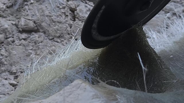 Close-up of a skilled artist using an angle grinder to cut and shape a fibre sculpture, captured in slow motion. The scene highlights precision craftsmanship, manual work, and industrial tools, India