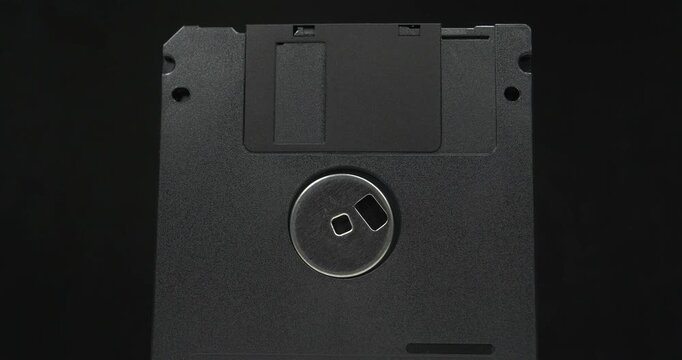 Black floppy diskettes. Floppy disk, diskette, or floppy diskette - type of disk storage made from a thin, flexible disk coated with magnetic storage medium. Cinema 4K 60fps video on black background