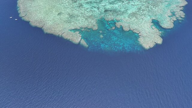 Seen from a bird's eye view, an impressive platform reef, named "E6," sits in the midst of the Bligh Channel east of Viti Levu, Fiji. The reef is home to extensive coral growth and fish diversity.