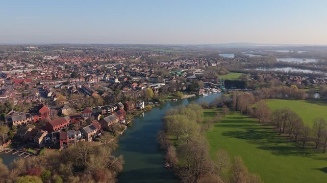 Aerial drone video of Reading in Berkshire, England, featuring the River Thames flowing through the town with surrounding urban landscape, bridges, and green spaces.