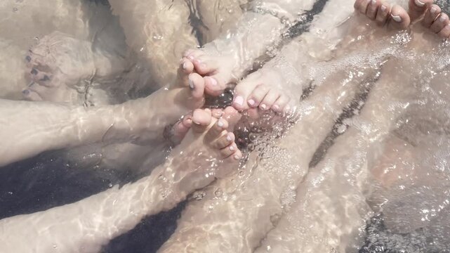 Close Up of Women's Feet Interacting in Bubbling Jacuzzi Water - Spa Relaxation and Wellness Concept in Horizontal 