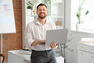Naklejka premium Young businessman working with laptop in office
