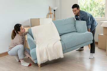 Moving house, relocation. Couple help set sofa and move furniture for new apartment, inside the room was a cardboard box contain personal belongings. move in the new apartment or condominium